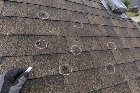 White chalk circles around dark bruise marks on a brown shingle roof