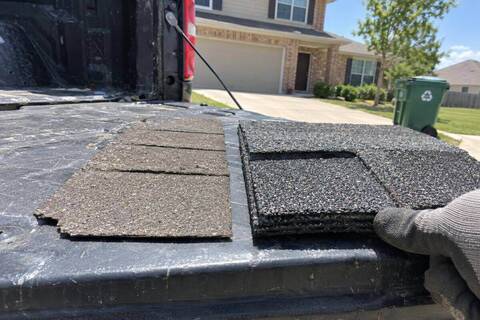 A thin three-tab shingle beside a thicker laminated shingle on a pickup tailgate